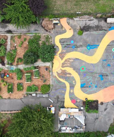 Overhead shot of Queens Community Justice Center mural next to garden featuring yellow and orange squiggly lines.